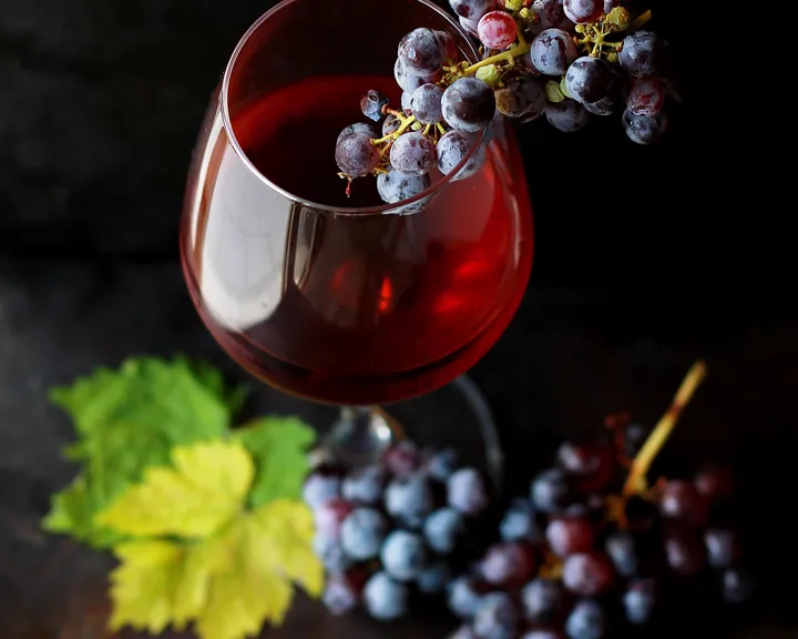Red wine in a glass with grapes balanced on top