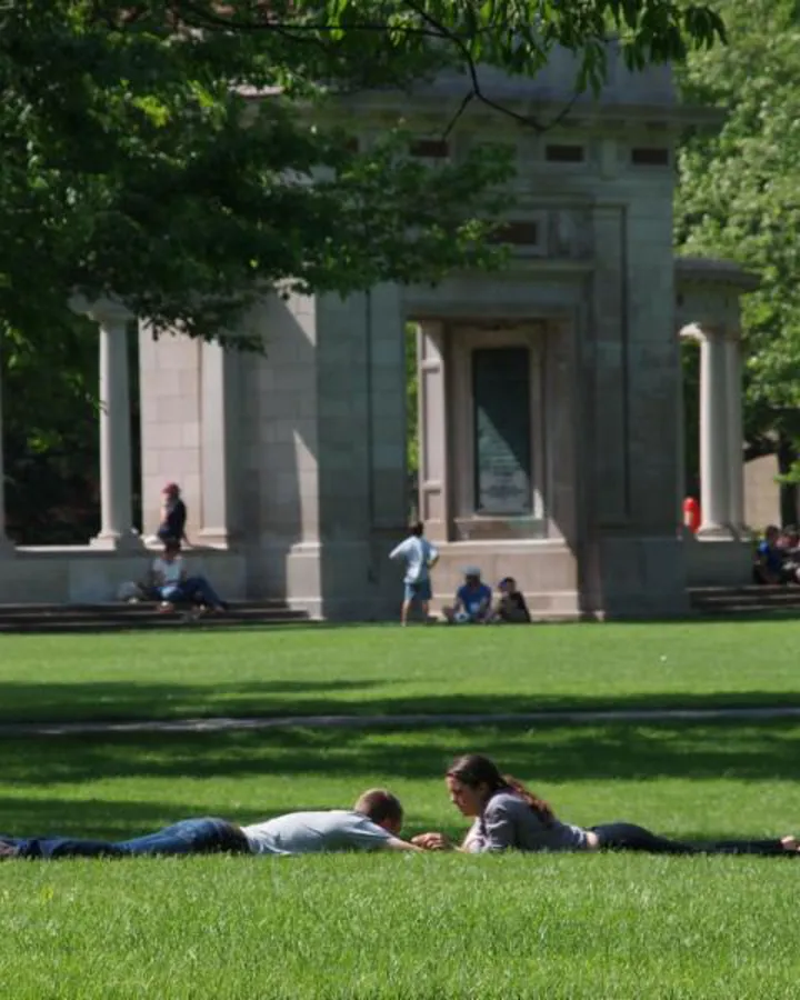 Two college students lying on the lawn in front of the arch at Oberlin College