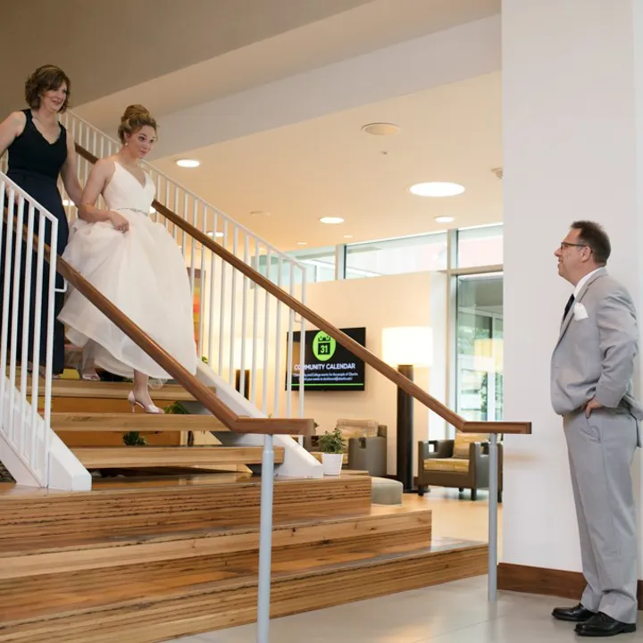 Bride walking down the stairs with her mother to meet her father
